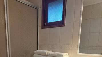 A bathroom with a toilet, a sink, a window, and a trash bin.