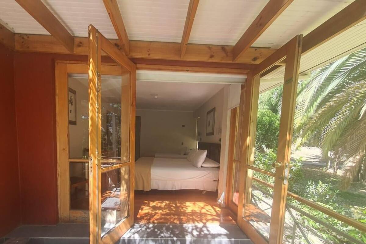 Un dormitorio con cama, ventana y vistas al verdor exterior.