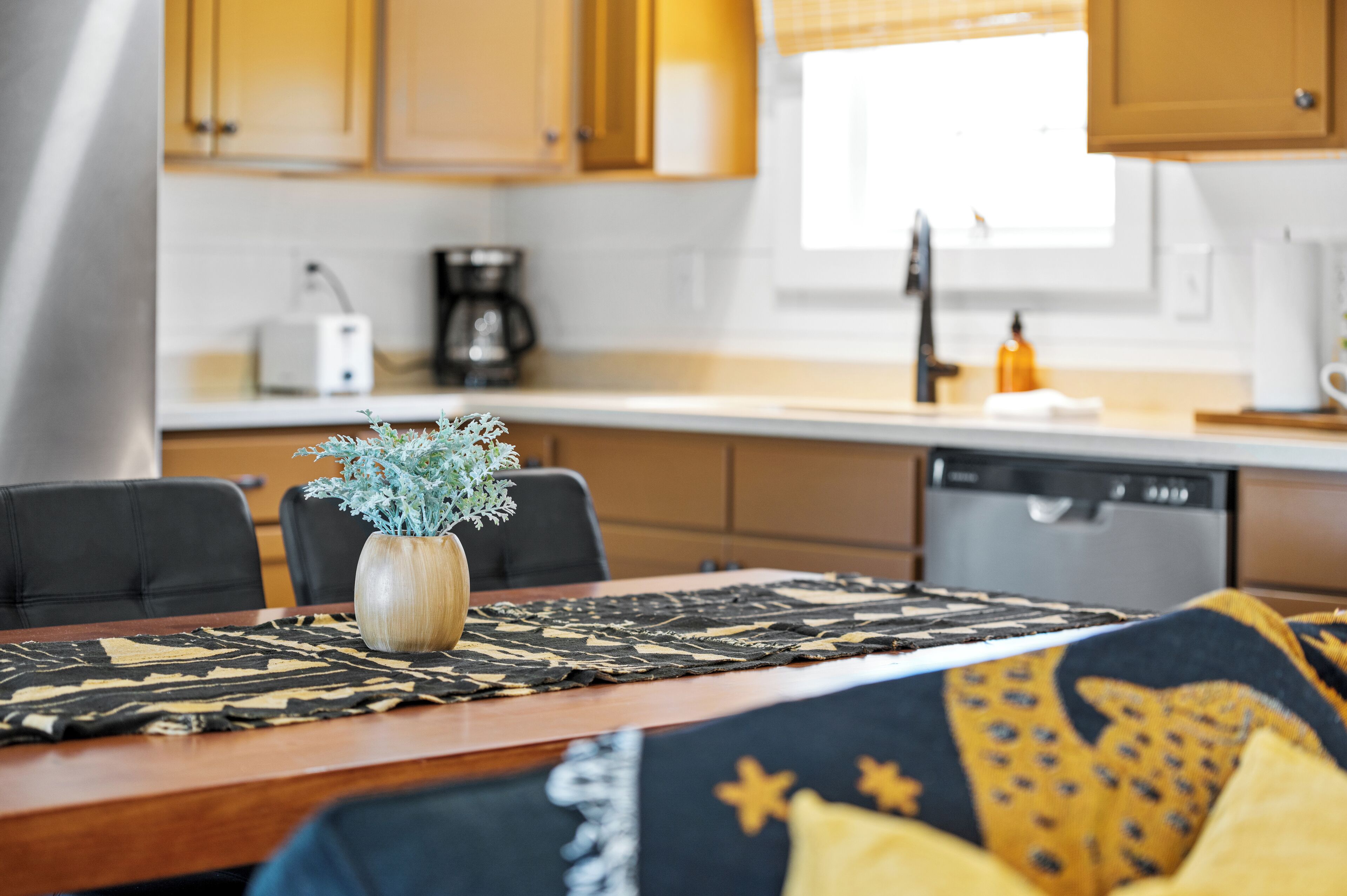 A modern kitchen with wooden cabinets, a coffee maker, and a dishwasher.