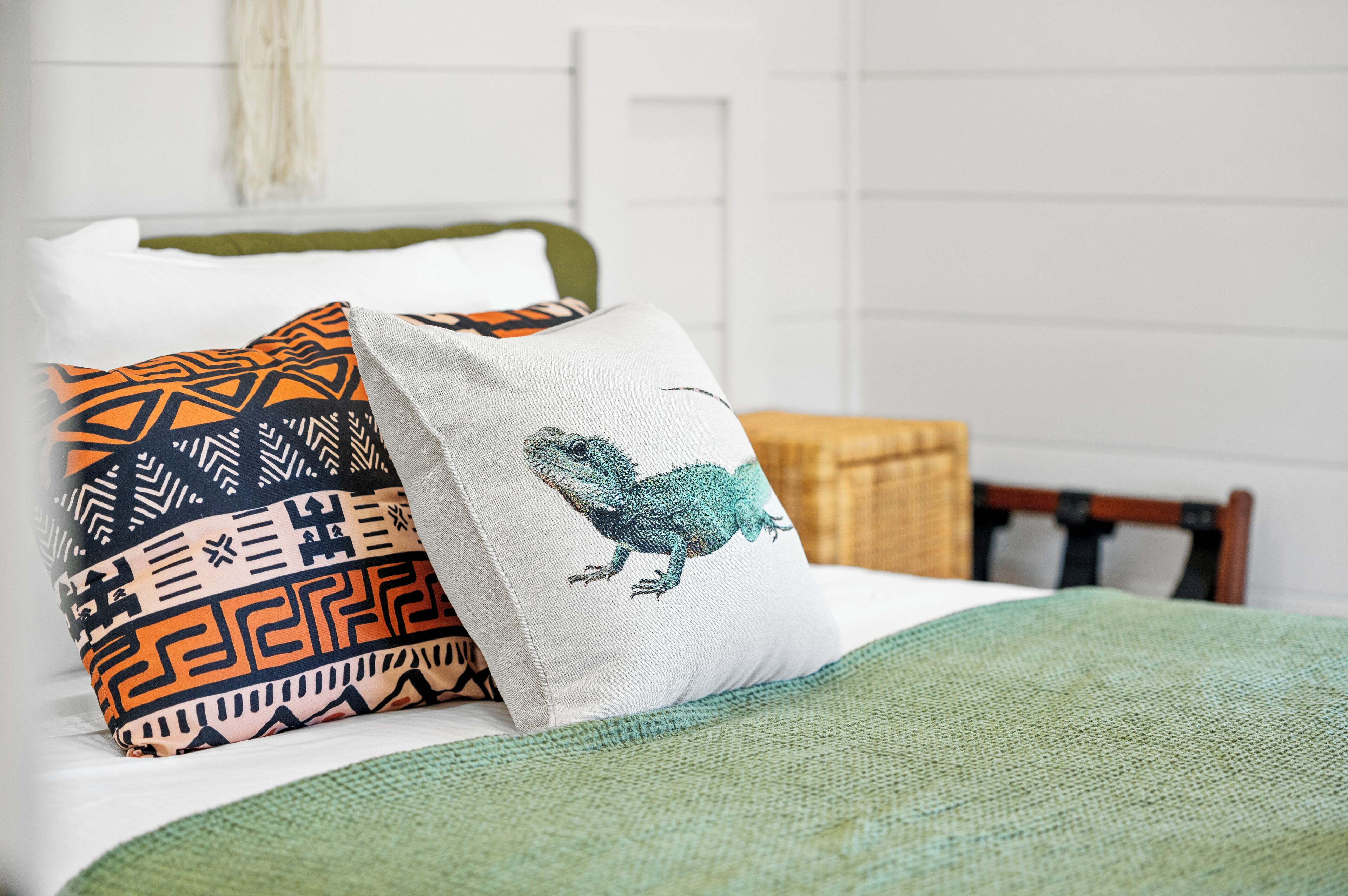 Un lit avec des coussins à motifs et une couverture verte.