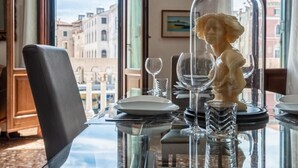Une table à manger avec un plateau en verre, une statue et des verres à vin.