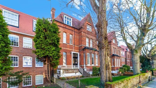 A red brick Victorian-style building with multiple windows, a front porch, and a well-maintained lawn. - Cosy 1-bedroom Apartment - Putney High Street (London)