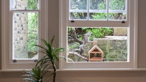 A room with a window overlooking a brick wall and greenery. - Cosy 1-bedroom Apartment - Putney High Street (London)