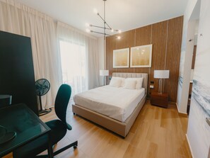 A modern hotel room with a large bed, a desk, a chair, and a desk lamp. - Downtown Punta Cana, walking distance to everything (Punta Cana)