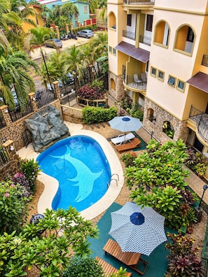 A residential area with a swimming pool, lounge chairs, and a stone wall. - Pura Vida Dreams (Tamarindo)