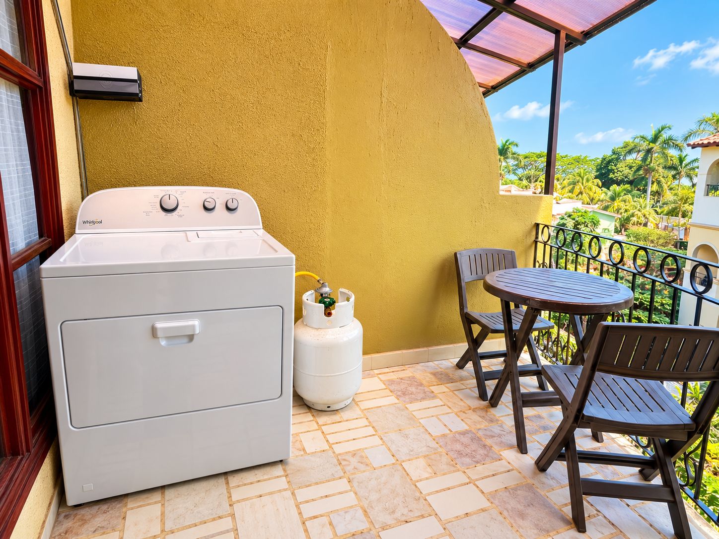 A laundry area with a Whirlpool washer and dryer, a gas tank, and a patio with a table and chairs.