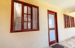A building facade with large windows and a door, featuring a textured wall and tiled flooring. - Pura Vida Dreams (Tamarindo)