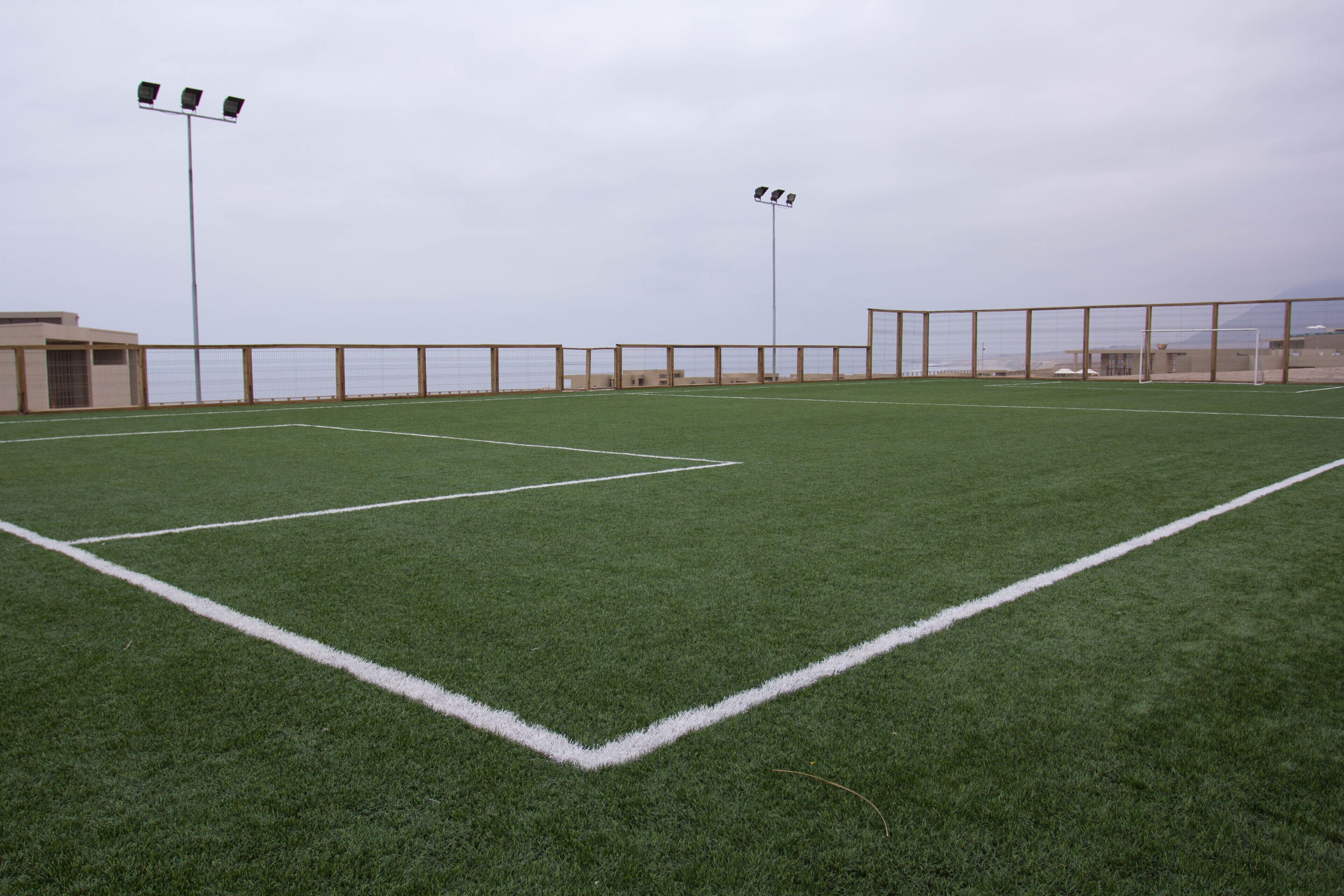 Un campo da calcio con porte, fari e vista sul mare.