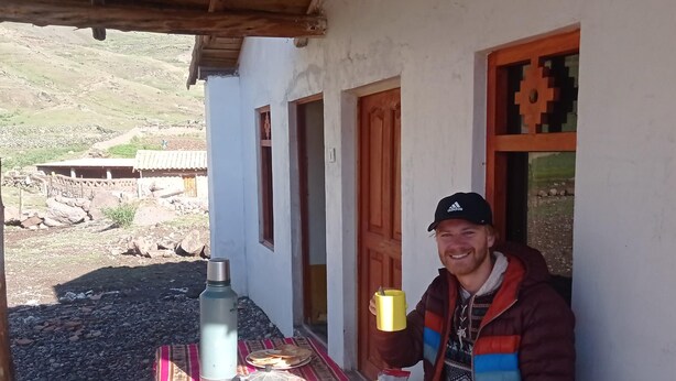 A person sitting at an outdoor table with a meal, a water bottle, and a thermos. - HOSTAL KINSA COCHA (Pisac)