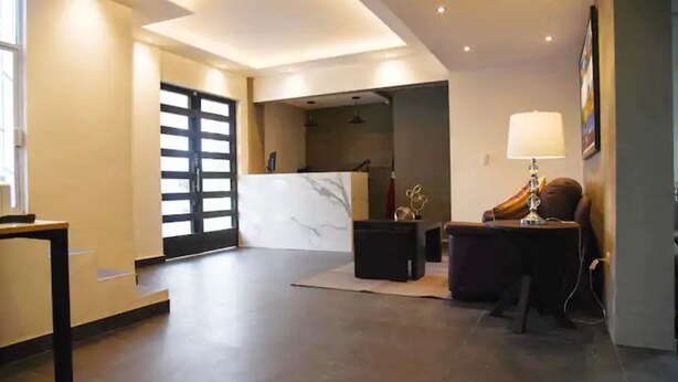 Een moderne lobby met een receptiebalie, een zithoek en een grote glazen deur naar buiten.