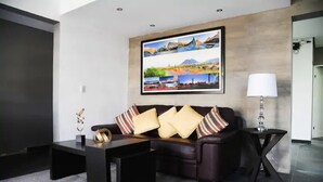 Een moderne woonkamer met een donkerbruine bank, een bijzettafeltje en een lijstwerk schilderij van een landschap erboven.