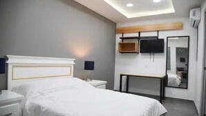Een moderne hotelkamer met een groot bed, nachtkastjes, een bureau, een flatscreen televisie en een spiegel.