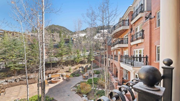 A courtyard with outdoor seating, a stone pathway, and a view of a mountainous area. - The Aspen Mountain Residences 19AB (Aspen)