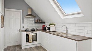 A modern kitchen with white cabinetry, a built-in oven, a microwave, and a sink.