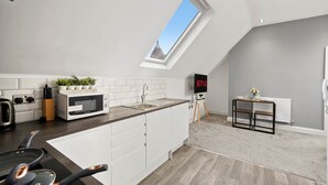 A modern kitchen with a skylight, white cabinets, a microwave, and a coffee maker.