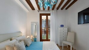 Un dormitorio con cama, una silla, un tocador y un televisor.