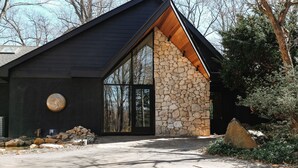 A modern building with a stone facade, large windows, and a black roof.