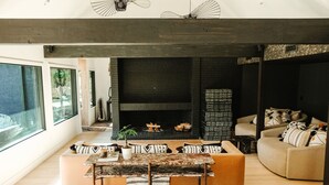 A modern living room with a fireplace, a sofa, and a dining area.