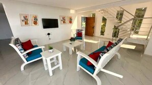 A modern living room with white sofas, a coffee table, and a flat-screen TV on the wall. - Luxury Beach Front Villa with Private pool and stunning Ocean View! (Punta Rucia)
