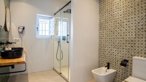 A modern bathroom with a glass-enclosed shower, a bidet, and a toilet.