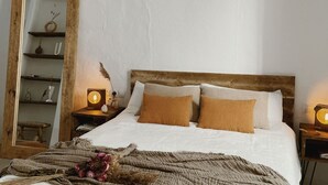 A bedroom with a large mirror, wooden headboard, white bedding, and two bedside lamps.