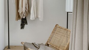 A room with a wicker chair, a floor lamp, and clothes hanging on a rack. - Salina Deluxe with balcony Room (Vejer de la Frontera)