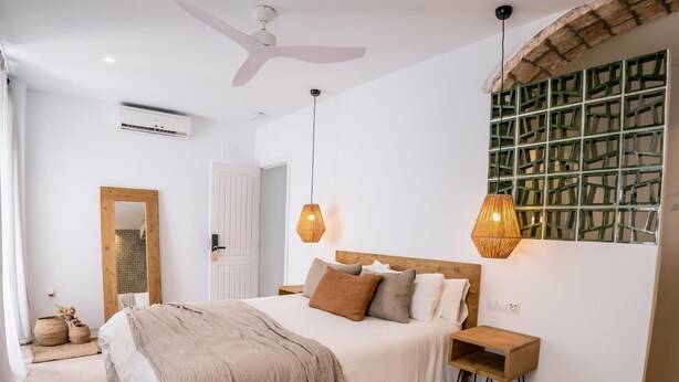 A bedroom with a bed, bedside tables, a mirror, and a green decorative wall. - Salina Deluxe with balcony Room (Vejer de la Frontera)