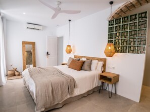 A bedroom with a bed, bedside tables, a mirror, and a green decorative wall.