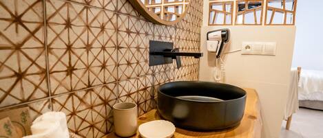 Une salle de bain avec un meuble-lavabo en bois, un lavabo noir, un bidet blanc et une serviette.