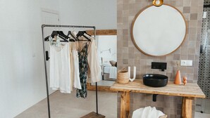 Une salle de bain moderne avec un meuble-lavabo en bois, un miroir rond et un porte-vêtements.