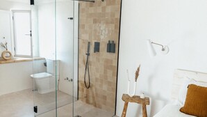 A modern bathroom with a glass-enclosed shower, a toilet, and a sink.