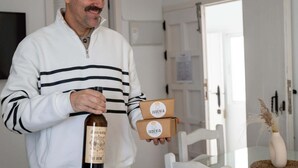 Una persona sostiene una botella y dos cajas, una de ellas con la etiqueta "JUDERIA".