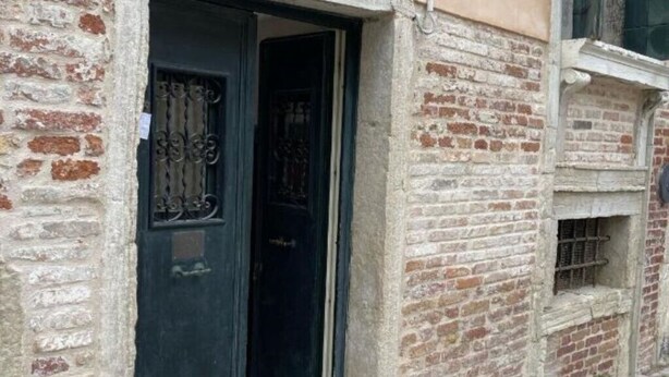 A brick building with a dark door and a window with metal bars. - Jesuit Apartment (Venezia)
