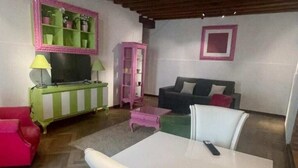 A living room with a green and white striped sofa, a red sofa, a white table, and a pink cabinet. - Jesuit Apartment (Venezia)