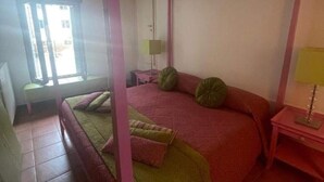 A bedroom with a four-poster bed, a bedside table with a lamp, and a window with blinds. - Jesuit Apartment (Venezia)