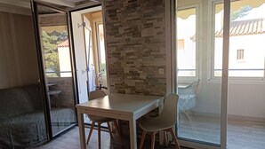 Une pièce comprenant une table et des chaises, un canapé et une porte-fenêtre coulissante donnant sur un espace extérieur.