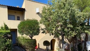 Un bâtiment à deux étages, doté d’une façade beige, d’une petite entrée à l’avant et d’un arbre dans le jardin.