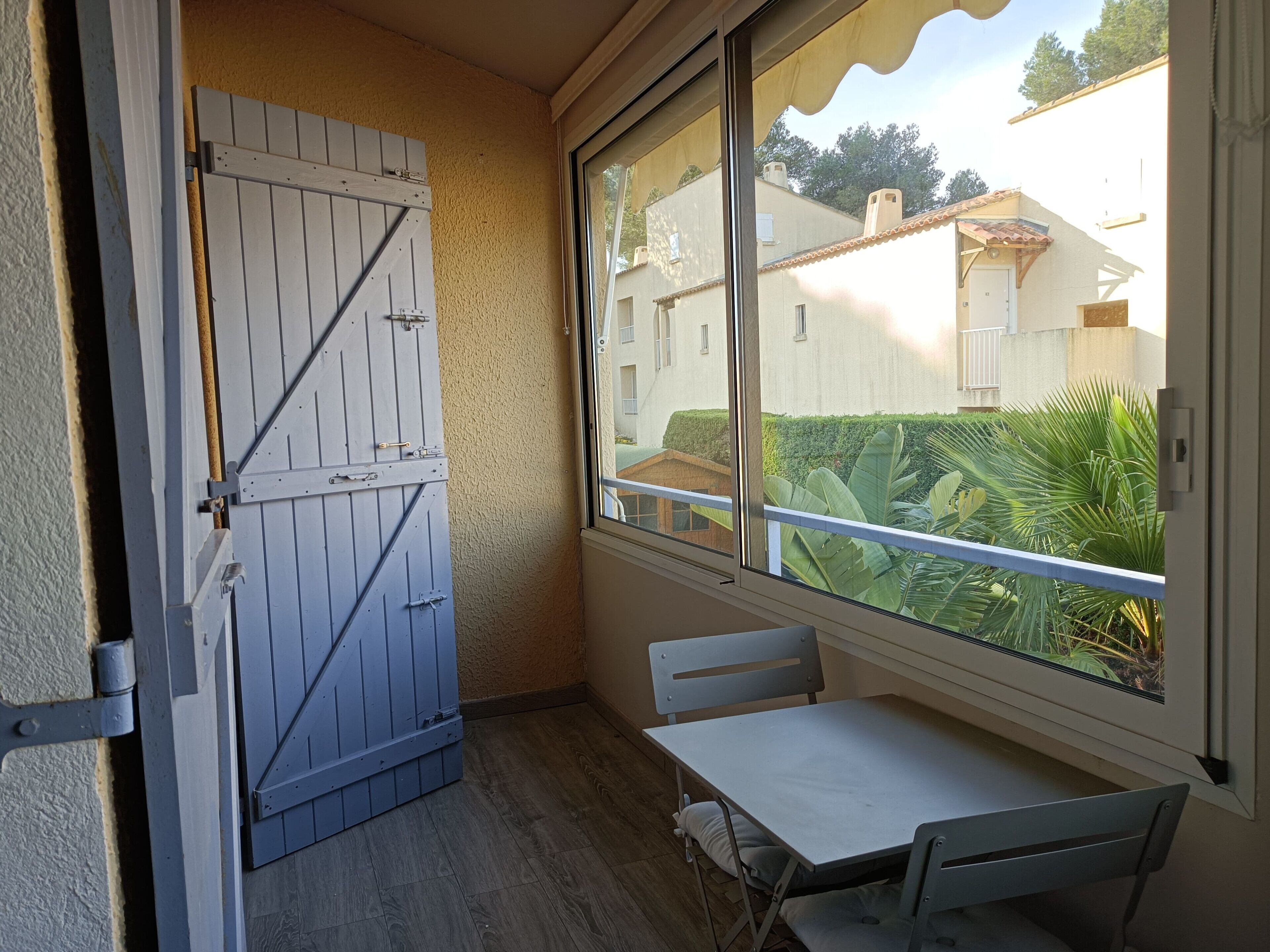 Ein Balkon mit einer Holztür, einem Tisch und zwei Stühlen.