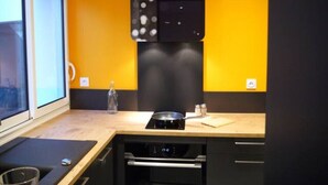 A modern kitchen with a black range hood, a window, and a wooden countertop.