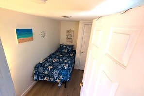 A bedroom with a bed, a door, and a wall with a painting.