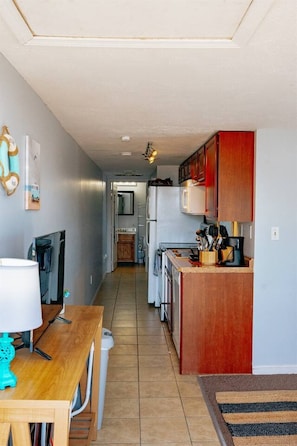 A compact kitchen with wooden cabinets, a refrigerator, and a dining area with a table and chairs.