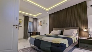 A modern hotel room with a large bed, a desk, and a view of the city. - Micasa-Sucasa Hotel and Suites (Port Harcourt)