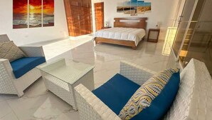 A modern hotel room with a large bed, a sofa, a coffee table, and artwork on the walls. - Luxury BeachFront Villa with Private pool and Ocean View!
 (Punta Rucia)
