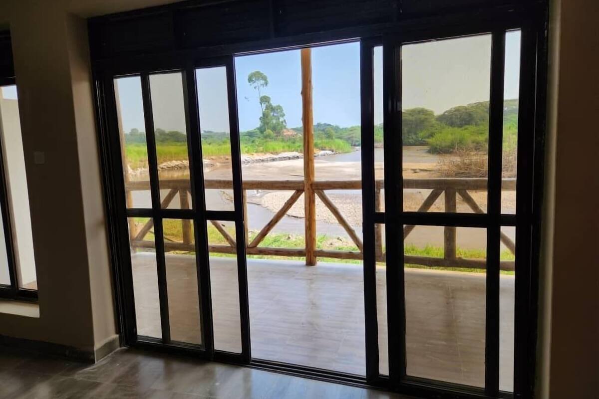A room with large windows offering a view of a river and greenery.