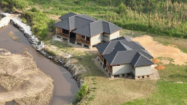 Un ryokan japonés tradicional con varias habitaciones de tatami, un sendero de piedra y un pequeño arroyo.