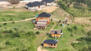 Una cabaña rural con varias cabañas, un río y follaje circundante.