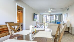 Een eetruimte met een houten tafel, stoelen en een plafondventilator.