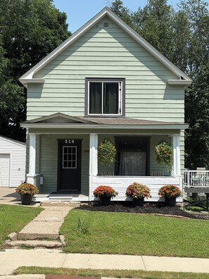 Une maison à deux étages avec un porche à l’avant, une porte noire et le numéro « 519 » sur la porte.