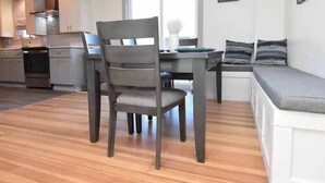 Et moderne køkken med lysegrå skabe, et spisebord med stole og en bænk med hynder.