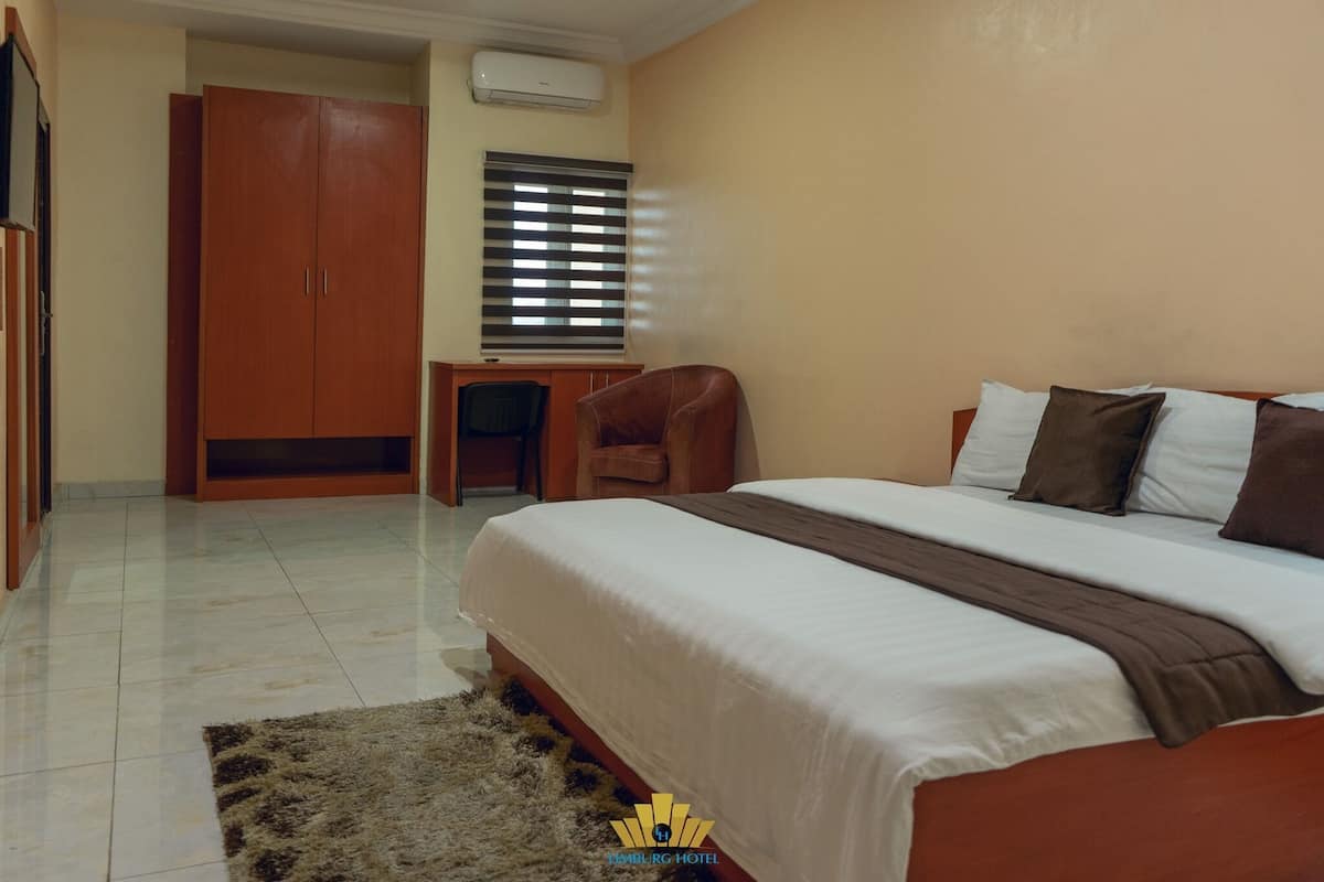 A hotel room with a bed, a desk, a chair, and a wardrobe.